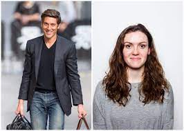 David wearing black coat with black jeans and also carrying bags in both hands and Dries wearing a grey sweater.